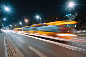A vibrant city street at night, showcasing the blur of a bus in motion amid bri, a Business Photo by ImageMir