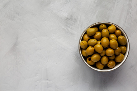 Marinated Green Pitted Olives in a Bowl, top view. Flat lay, ove, a Food & Drink Photo by LiudmylaChuhunova