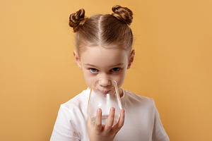 Young girl with twin buns drinks from a clear glass against a vi, a Person Photo by Ales Munt