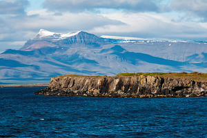 Rocky coastline with Akranes mountainscape and blue waters in Iceland, a Photo by AS photostudio