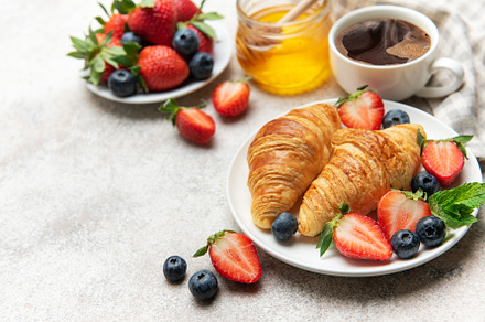 Delicious breakfast with croissants, coffee, berries and honey e