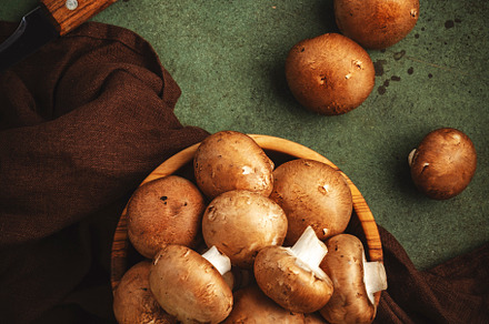 Fresh brown champignon mushrooms in wooden bowl, green stone kit, a Food & Drink Photo by 5PH