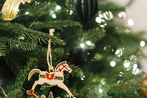 Horse christmas toy hanging on tree branch with festive lights., a Holiday Photo by Sonjachni