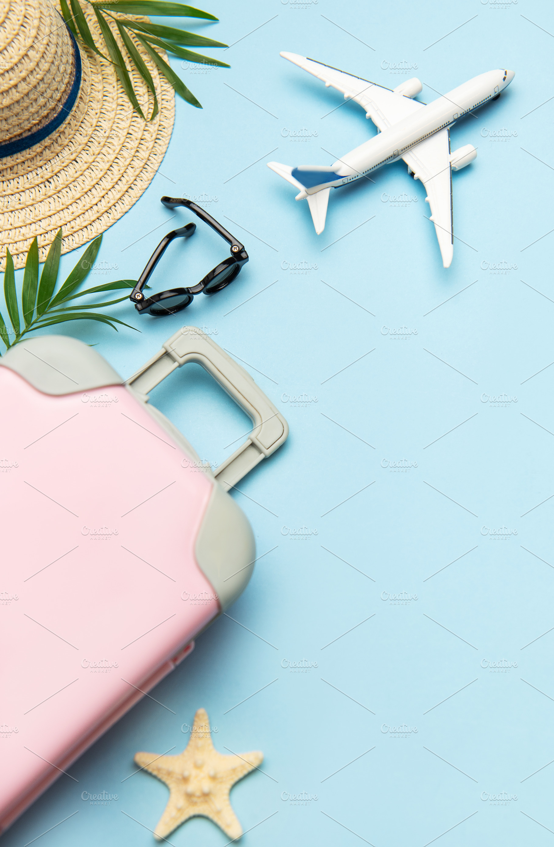 Pink suitcase, airplane model, sunglasses and straw hat on blue, a Holiday Photo by Olena Rudo