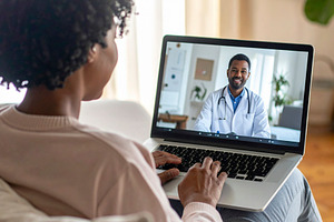 Woman atient at home using a laptop for a telemedicine consultat, a Health & Medical Photo by DanFLCreativo