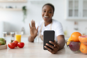 Glad millennial african american woman waving hand, taking photo on phone on ta, a Person Photo by Prostock-Studio
