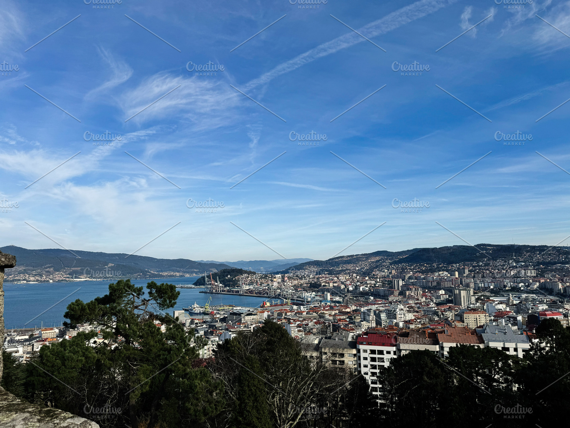 Panoramic view of Vigo cityscape and harbor under a vibrant blue sky, a Photo by AS photostudio