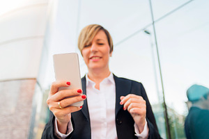 Business woman using smartphone outdoors, a Photo by RF Images