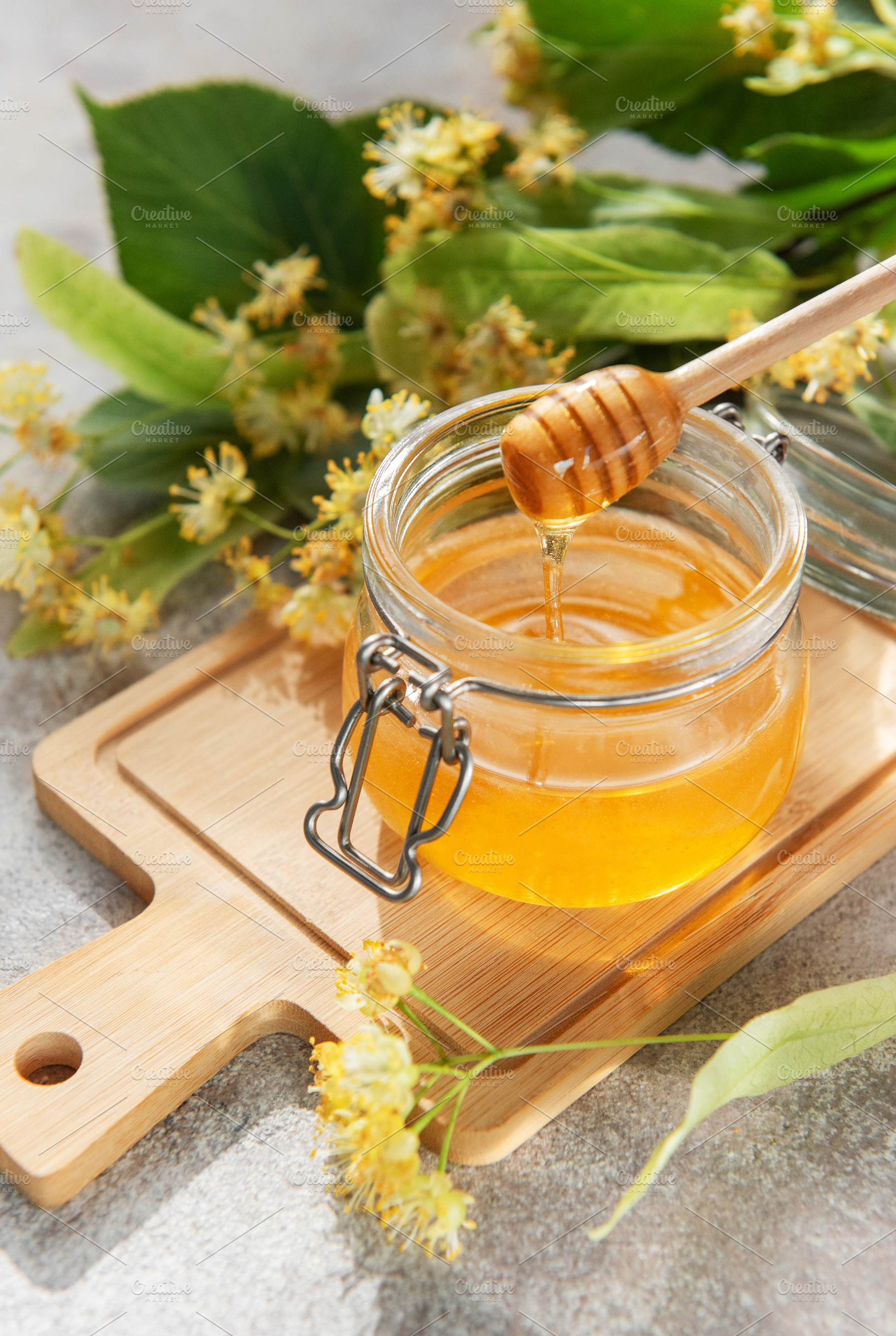 Golden linden honey jar with dipper on wooden board, a Food & Drink Photo by Olena Rudo
