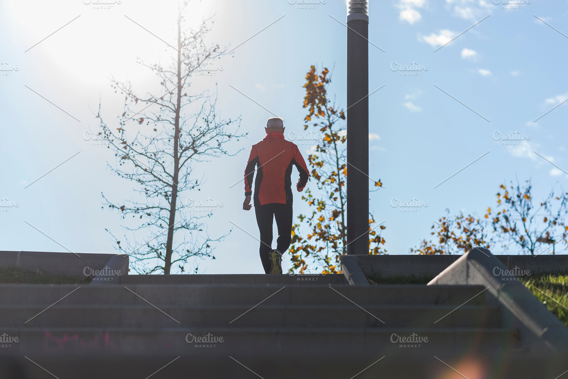 Active senior man climbing stairs in outdoor park sunlight, a Sports & Recreation Photo by RF Images