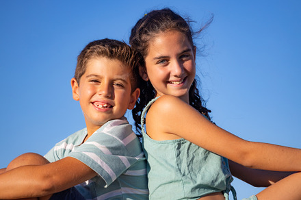 Two relaxed kids against blue sky at summer