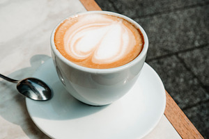 macchiato with heart shaped foam on a terrace table, a Photo by Nito