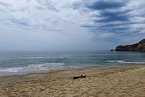 Serene coastal view of a sandy beach with cliffs under a cloudy sky, a Photo by AS photostudio