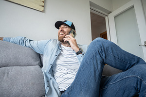 Man talking on smartphone sitting on sofa at home, casual lifestyle, a Person Photo by etorres69