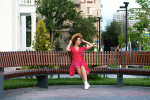Woman adjusts straw hat while seated, a Person Photo by Elena Vagengeim