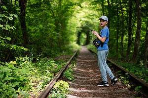 Boy Walking Along Overgrown Railroad Tracks Through a Forested Environment, a Photo by AS photostudio