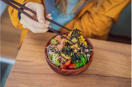 Woman eating Raw Organic Poke Bowl, a Food & Drink Photo by Elizaveta Galitskaya