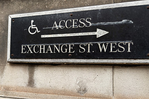 Black accessibility sign for Exchange St West with wheelchair ar