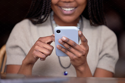 Closeup, black hands and smartphone for connection, typing and search website for information. Zoom, African American female and lady with cellphone, social media or networking with signal and smile, a Photo by Peopleimages.com
