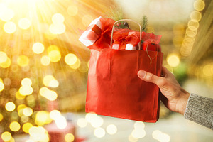Hand holding shopping bag full of gifts outside sunny, a Holiday Photo by Davizro's Market