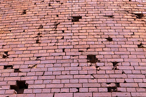 An old brick wall with various damages, a Photo by rsoollAI
