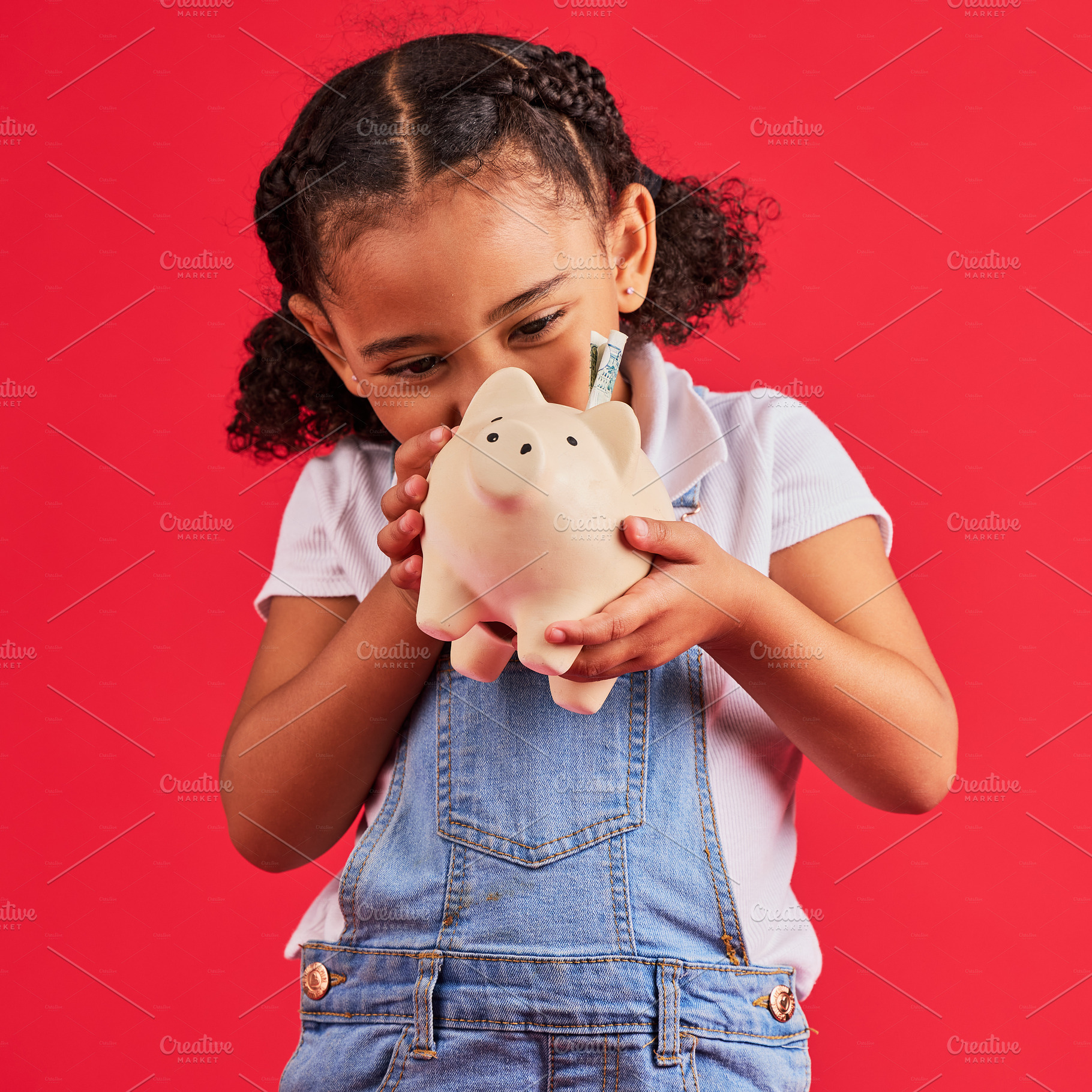Little girl, excited and piggy bank savings in money planning, finance management or future investment on isolated red background. Smile, happy child and cash box in finance growth or budget learning, a Photo by Peopleimages.com