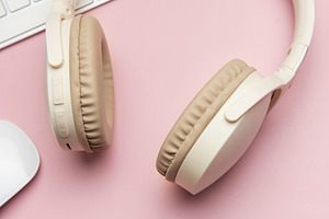 Wireless headphones, keyboard and mouse lying on pink table, a Business Photo by Olena Rudo