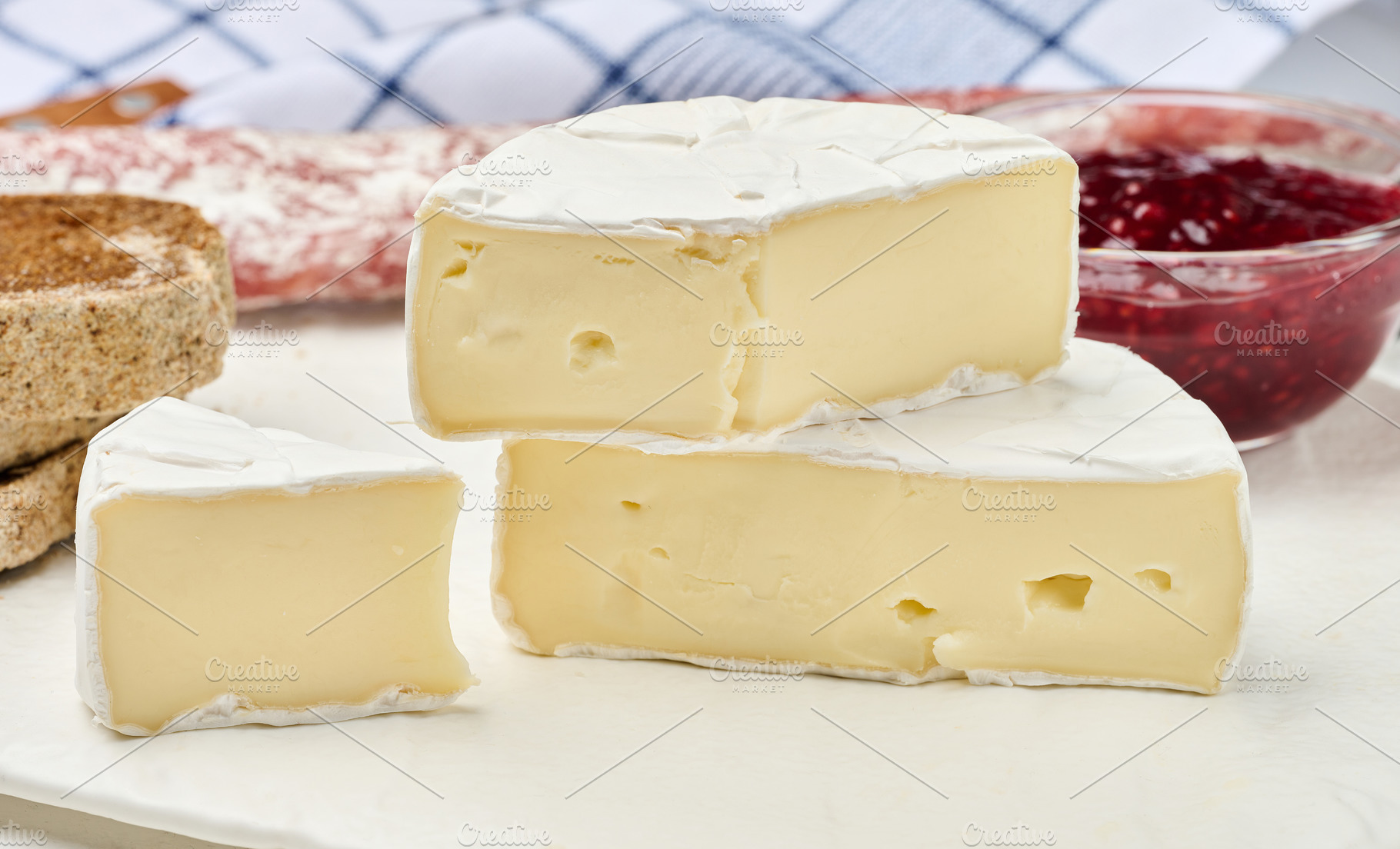 Sliced round head of Camembert cheese on a white board and, a Food & Drink Photo by ndanko
