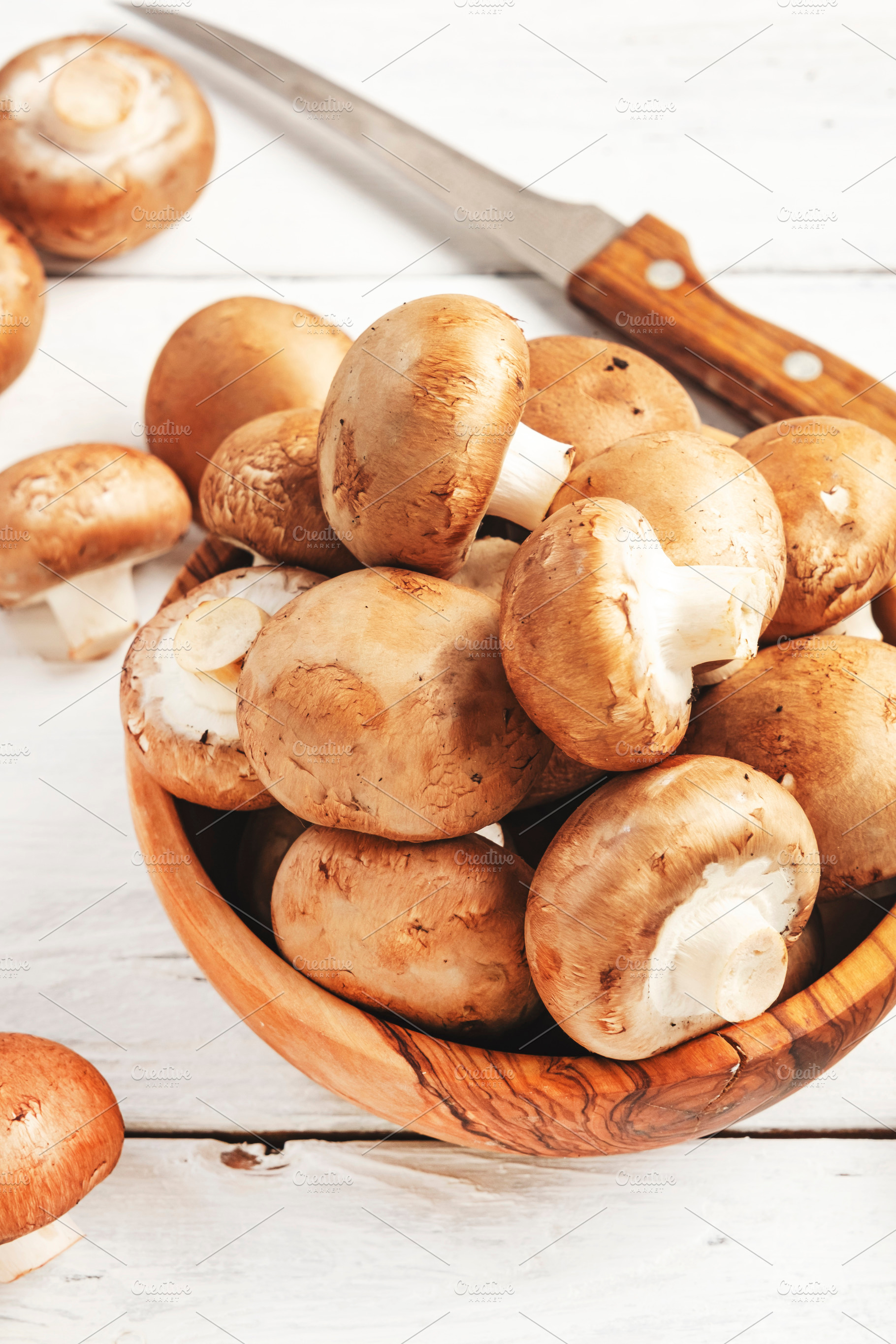 Fresh brown champignon mushrooms in wooden bowl, white wooden ki, a Food & Drink Photo by 5PH