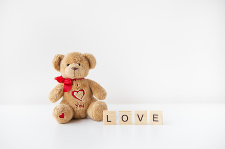 Cute toy teddy bear with a heart isolated on a white background. Love lettering, an Abstract Photo by Artsaba Family