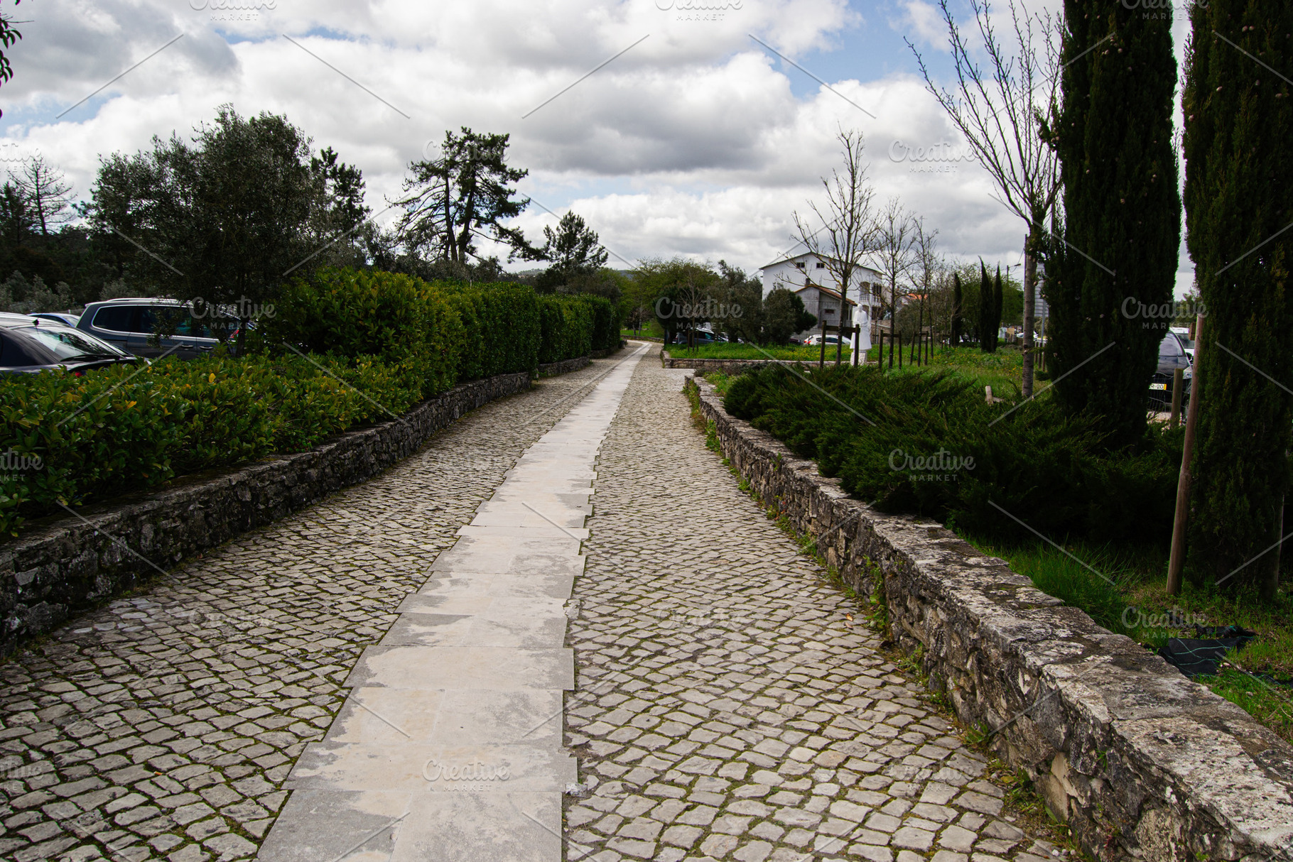 Stone pathway surrounded by greenery in Fatima, Portugal on a cloudy day, a Photo by AS photostudio