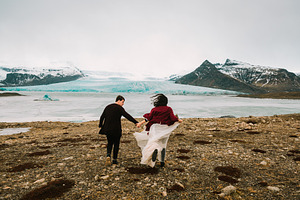 Bride and groom runs together iceland wedding in glacier lagoon rear view