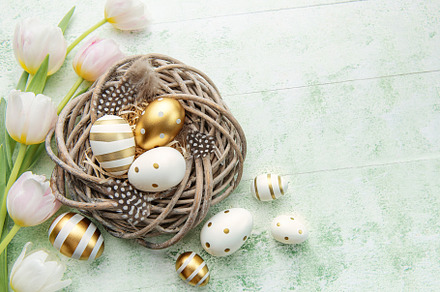 Nest with Easter eggs painted golden colors on a green wooden ba, a Holiday Photo by Olena Rudo