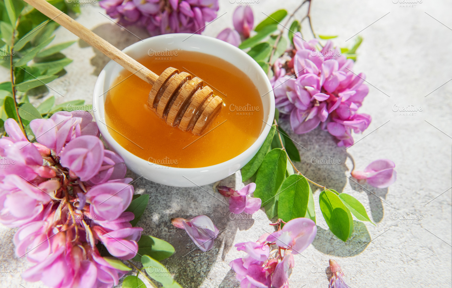 Acacia honey in bowl with honey dipper and flowers, a Food & Drink Photo by Olena Rudo