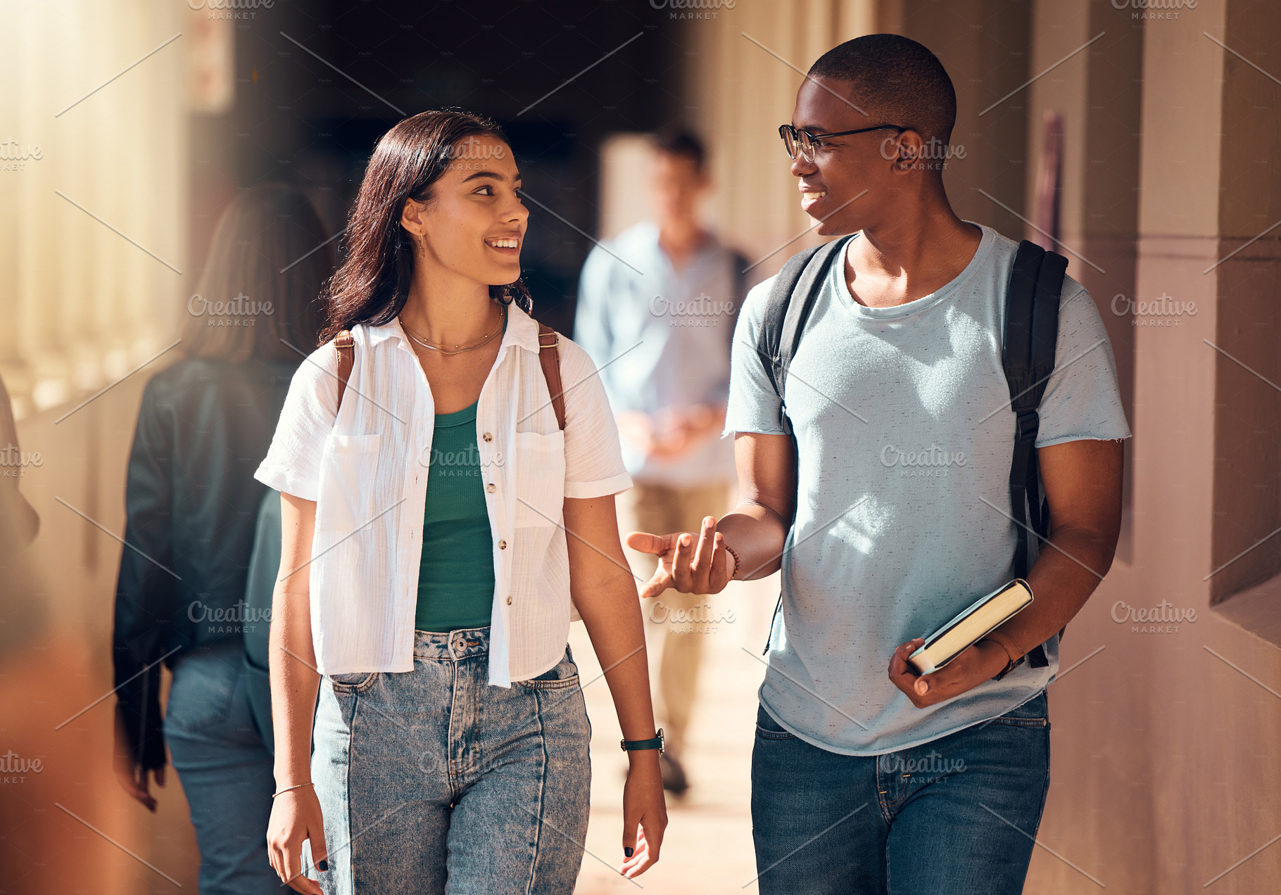 Education, students and friends on campus for university, learning and conversation, walking to class and academic goals with book. Young, woman and man with college and study, learn with scholarship, a Photo by Peopleimages.com