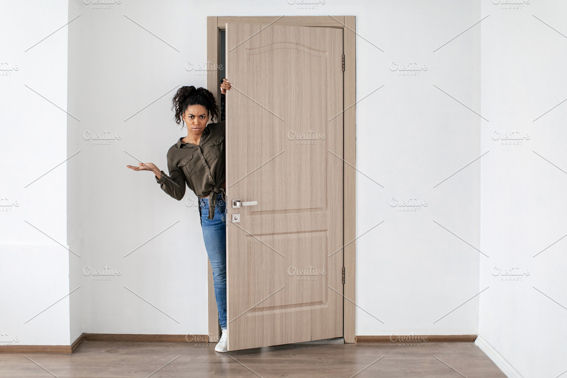 Discontented Black Lady Opening Door Looking At Camera At Home, a Photo by Prostock-Studio