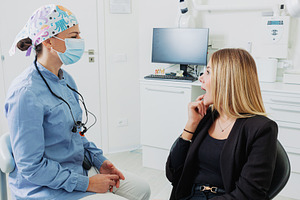 Dentist wearing surgical mask listening to patient explaining toothache in brig, a Health & Medical Photo by Antonio Gravante Market