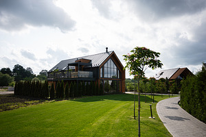 Modern wooden house surrounded by a lush green lawn and a paved pathway, a Photo by AS photostudio