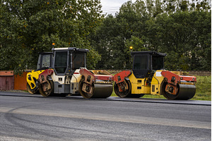Two road rollers parked on highway, an Industrial Photo by volodymyrshtun13795