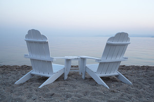 Empty wooden deck chairs on a beach featuring chair, two, and nobody, a Person Photo by Grey Coast Media