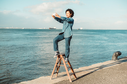 Man on ladder taking selfie by water, a Person Photo by SkyNext