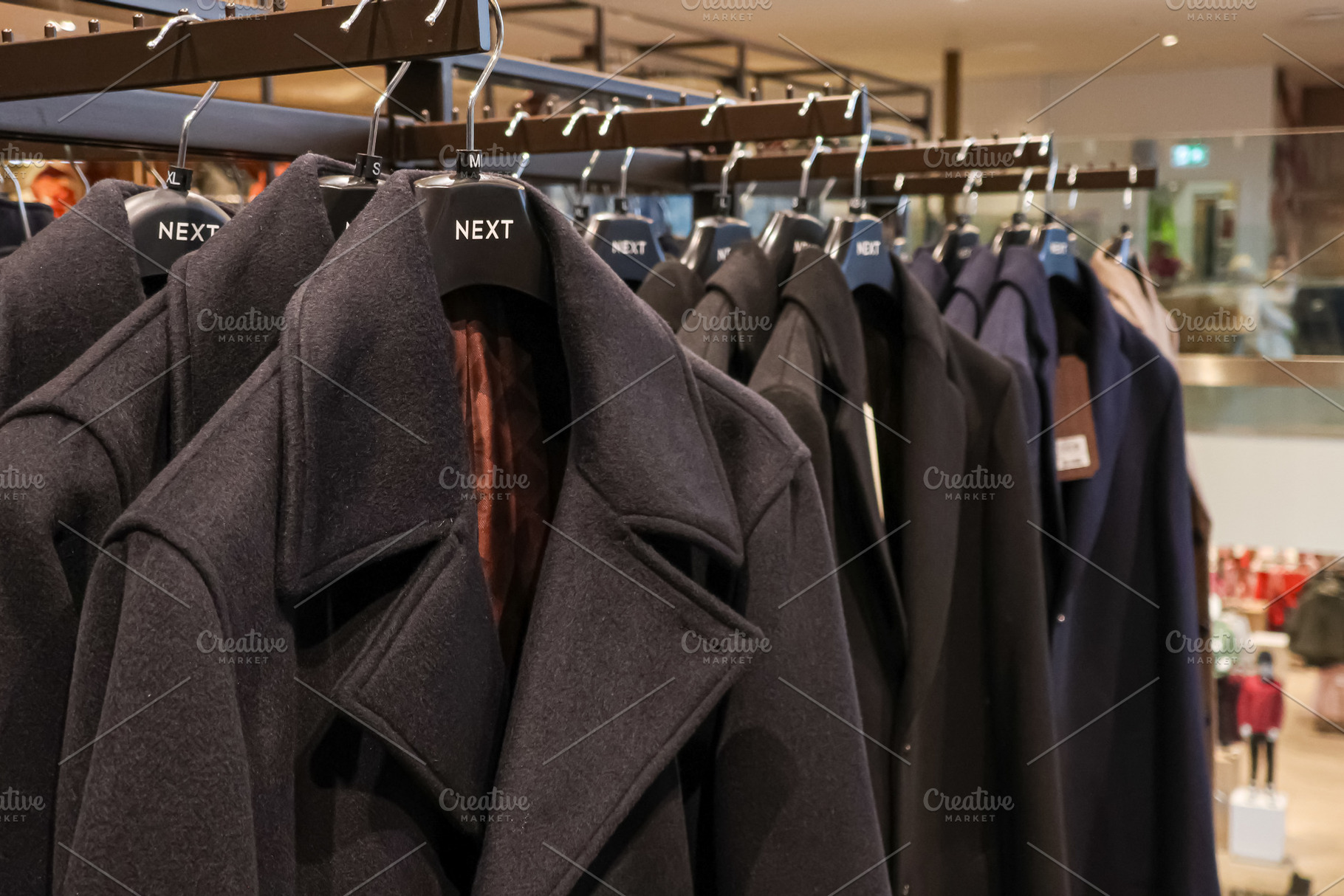 Winter coats hanging on retail rack in clothing store, offering warmth and styl, a Photo by Studio ANNA