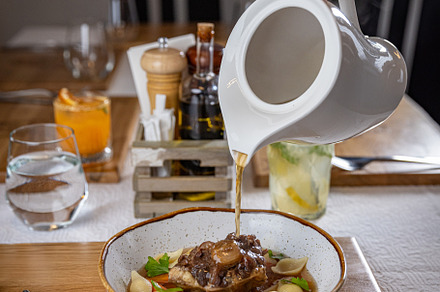 Waiter pouring broth
