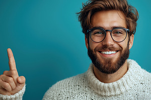 Smiling bearded man with glasses pointing upward against teal ba, a Person Photo by José Manuel Gelpi