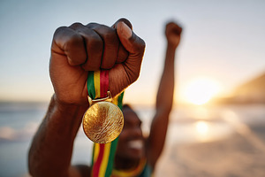 Victorious man celebrates achievement at sunset with raised fists and medal in, a Person Photo by AlyaAnd