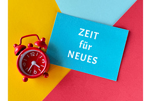Red alarm clock and blue card with, a Photo by tilialucida