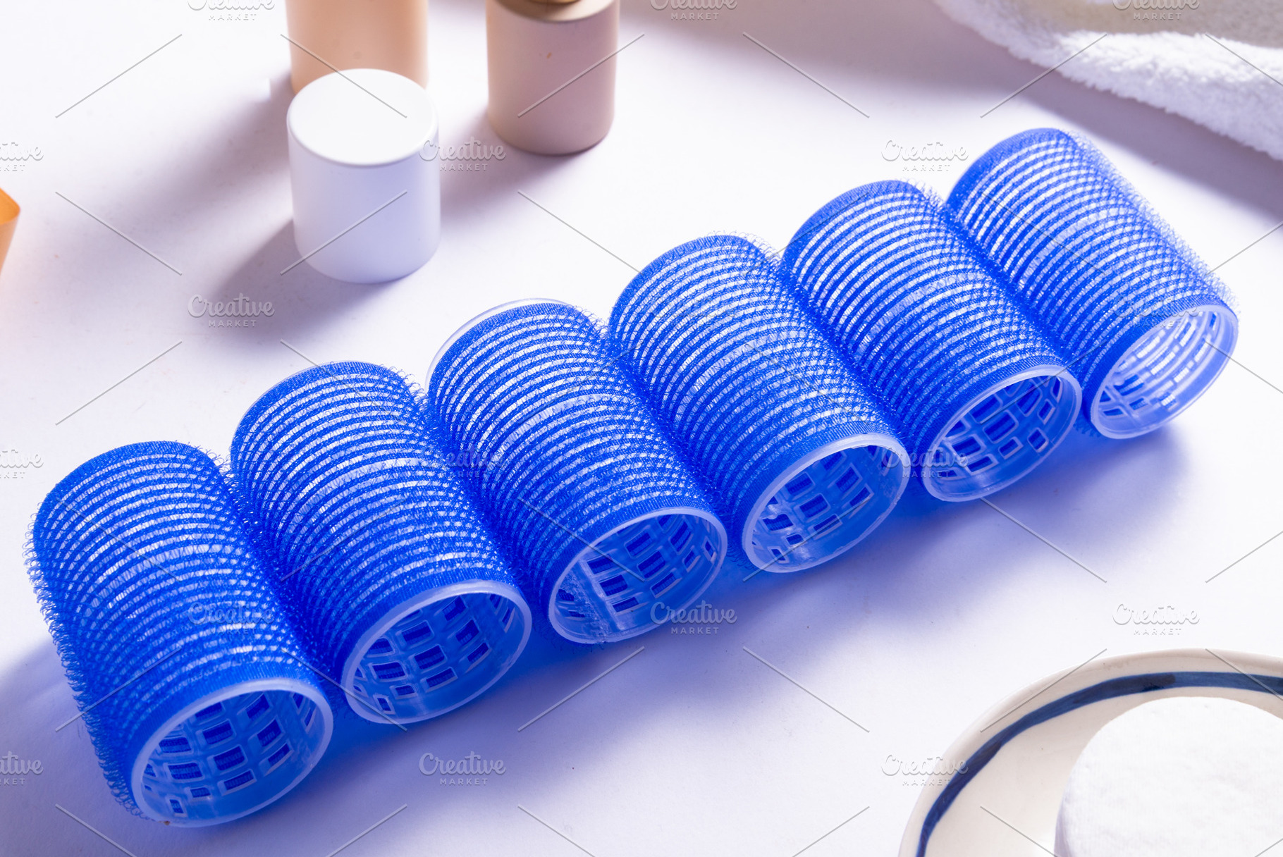 Set of Blue Plastic Hair Rollers with Hair Care Products on Whit, a Business Photo by MDBildes