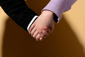 Closeup of two children holding hands on a beige background, sym, a Person Photo by Ales Munt