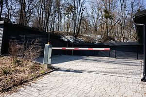 Closed parking gate in a forested area with bare trees in early spring, a Photo by AS photostudio