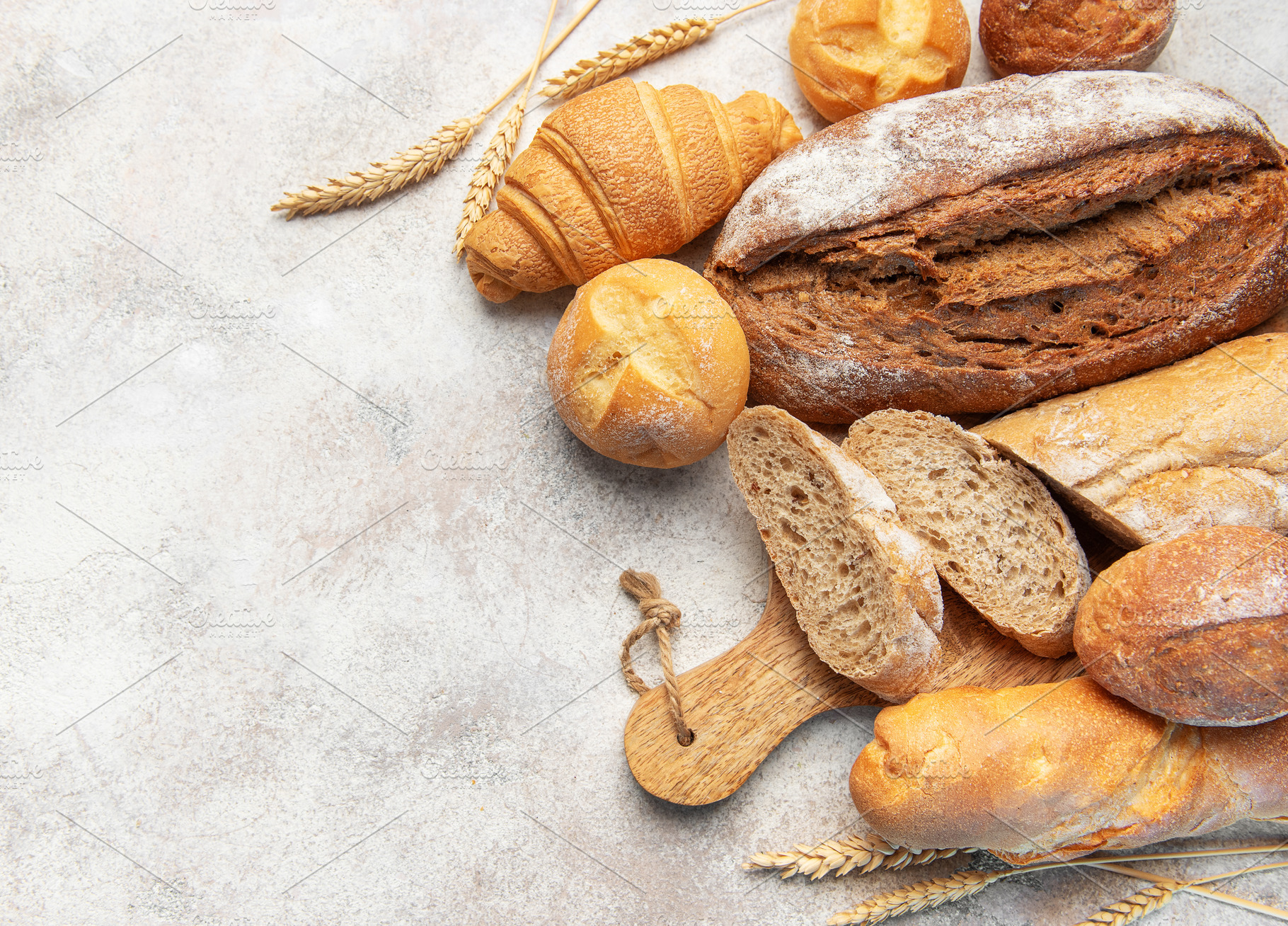 Assorted fresh bakery bread products on textured background, a Food & Drink Photo by Olena Rudo